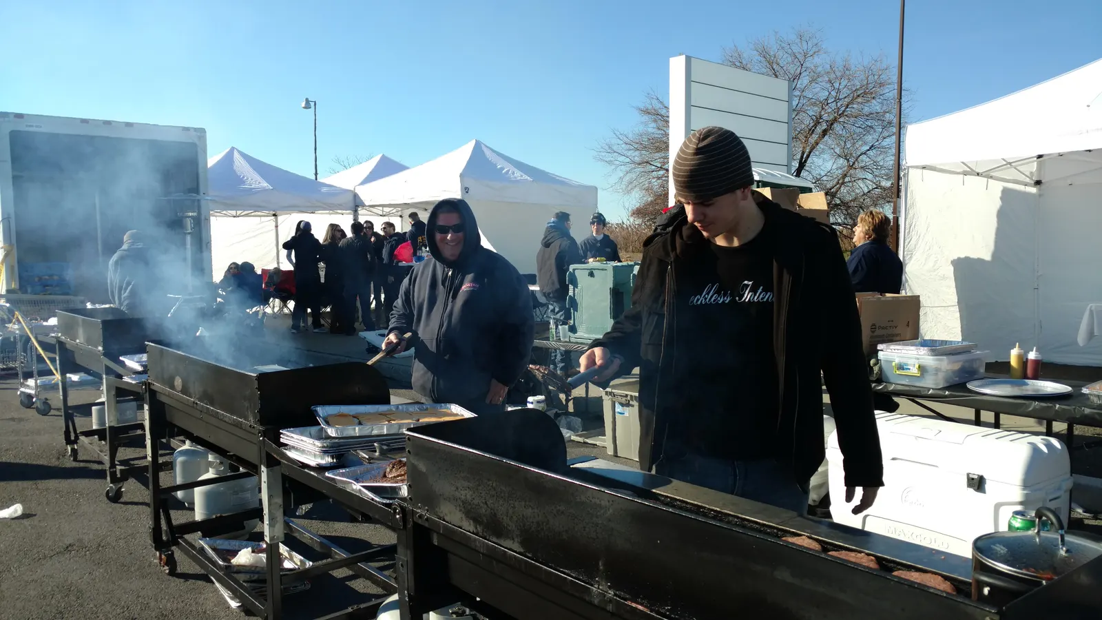 The crew grilling burgers on the flat-tops, smoke rising