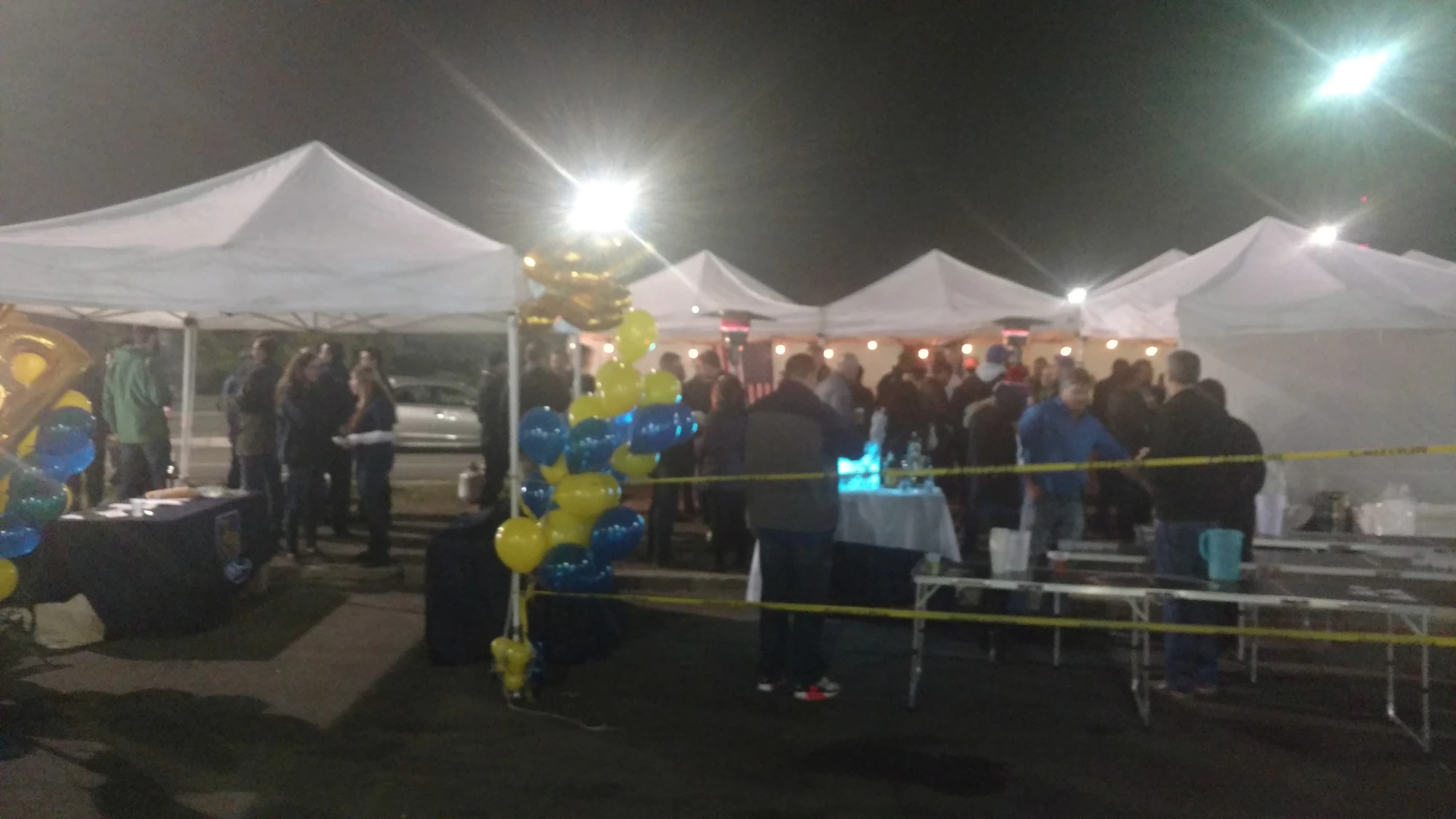 A night tailgate lit up under the tents