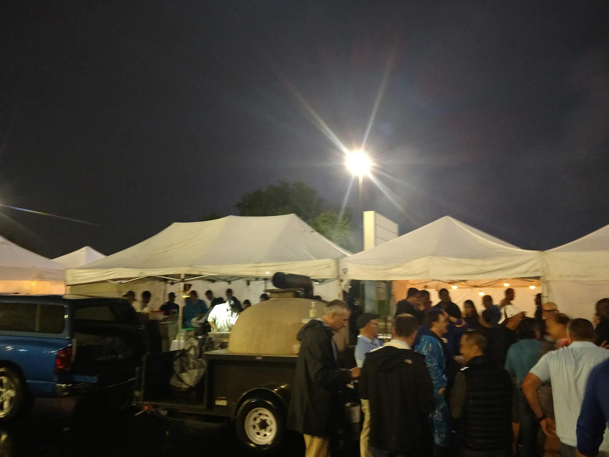 Lit tents and a crowd at a night-game tailgate